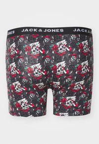 Schwarze Boxershorts mit einem Muster aus Totenköpfen, Rosen, Zuckerstangen und Noten, mit einem schwarzen Bund, der mit "JACK & JONES" gekennzeichnet ist.