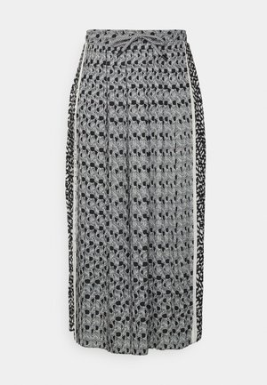 Schwarz-weiß gemusterter Maxirock mit gebundenem Bund. Besitzt eine Mischung aus abstrakten Designs und Texturen. Fließender Stoff mit seitlichen Akzenten.