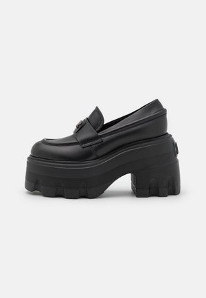 Zwarte leren loafers met een robuuste plateausole. De zool heeft een gestructureerde grip en een ronde neus. Glad afwerking met een subtiele logo-detail.