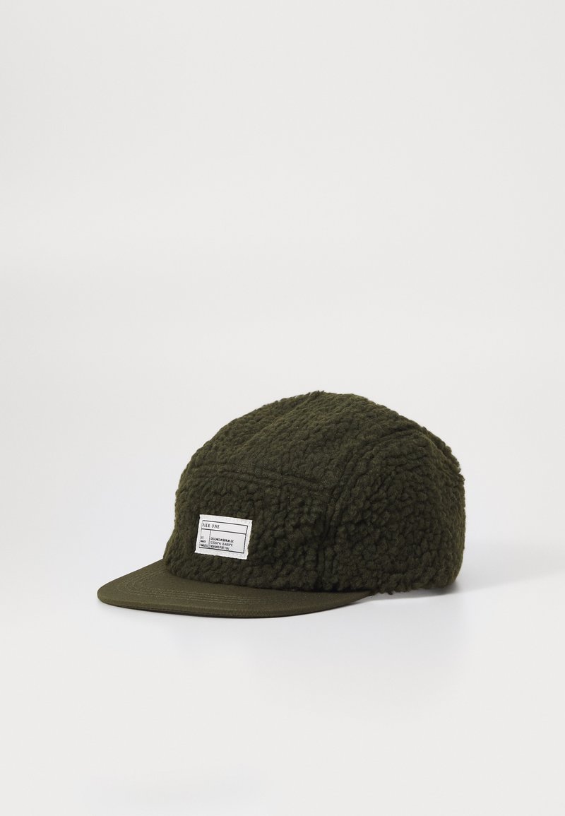 Olívazöld sapka strukturált fleece anyagból, merev elülső vizorral és fehér címkével. A design strukturált panelekből áll.