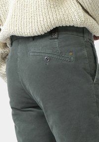 Graue Cordhosen mit strukturierter Oberfläche, ausgestattet mit einer Gesäßtasche mit Knopf und einem gewebten Gürtel-Detail.