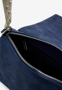Marineblaues Leder-Handtasche mit glatter Textur, ausgestattet mit einem Reißverschluss und silberfarbenen Beschlägen. Der Innenraum zeigt eine Tasche und Details zur Fütterung.