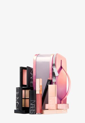 Set di trucco con una pochette a gradi di rosa, packaging dei prodotti in nero e oro rosa, che include rossetti, fard e una palette.