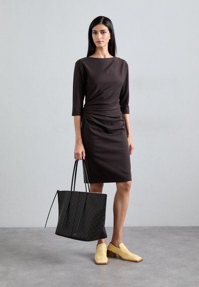 Brown fitted dress with three-quarter sleeves, gathered detail at waist, paired with a textured black tote bag and woven yellow shoes.