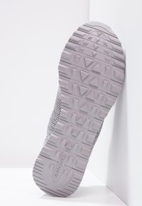 Grå sportskor med en texturerad mesh-övre, utrustad med en gummisula med geometriska mönster och "Skechers"-logotyp.