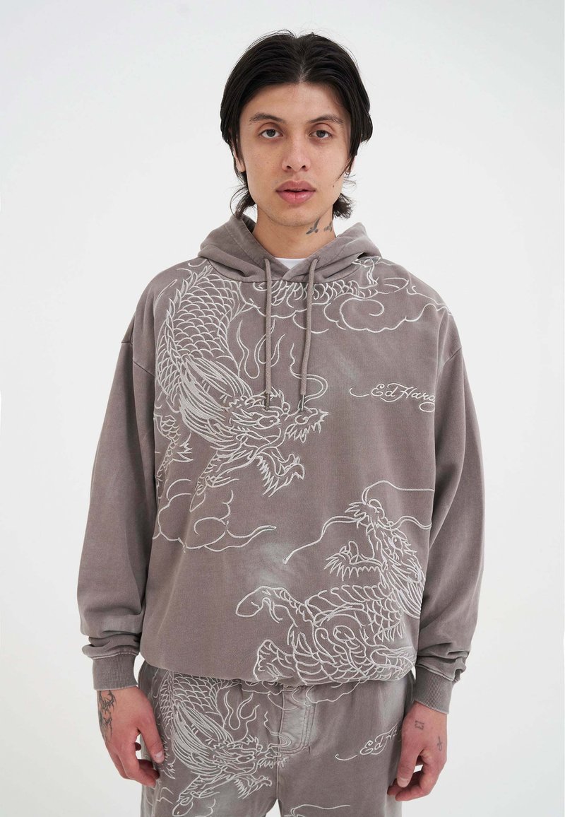 Grå hoodie med drakdesign i vit brodyr, med lös passform, dragkedja för huvan och ribbade muddar. Enkla byxor i matchande tyg.