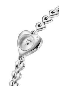 Ασημένιο ρολόι σε σχήμα καρδιάς με γυαλιστερή επιφάνεια, που διαθέτει απλό καντράν και μπρασελέ από διασυνδεδεμένους συνδέσμους σε σχήμα καρδιάς.