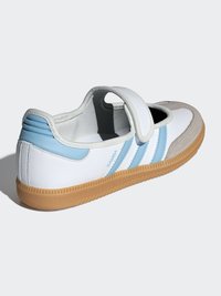 Biela a svetlomodrá teniska s prackou na suchý zips, textúrovanou gumovou podrážkou a tromi modrými pruhmi na boku. Jemné kožené a semišové materiály.