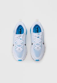 Scarpe da ginnastica bianche con accenti blu, tomaia in rete e branding nero. Presentano un design con lacci e un colletto imbottito per il massimo comfort.
