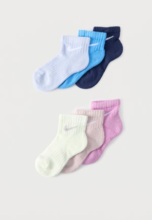 Six chaussettes basses Nike en blanc, bleu clair, marine, crème, beige et rose, disposées en deux rangées sur un fond blanc.