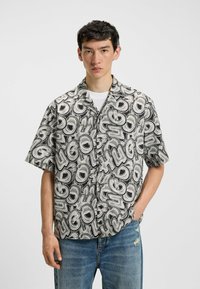 La camicia a maniche corte con bottoni presenta un motivo lucido nero e grigio con il testo ripetuto "HUGO". Realizzata in tessuto morbido, ha una vestibilità comoda.