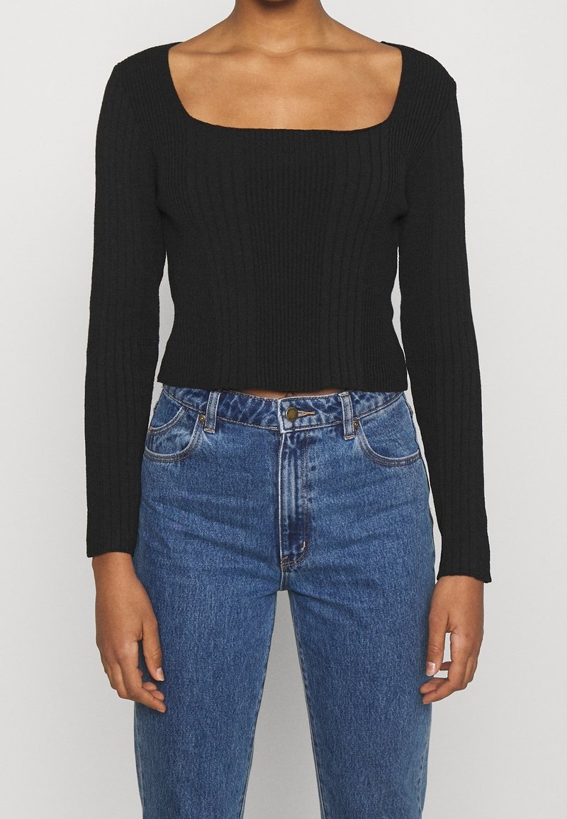 Crop top noir à manches longues côtelé avec un col carré, associé à un jean bleu taille haute avec un design classique à cinq poches.