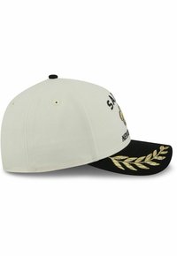 Light beige cap with a black visor, featuring gold leaf embroidery on the brim and decorative lettering on the front.