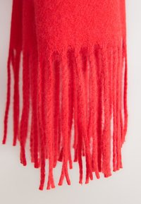 Écharpe en laine rouge avec une texture douce, présentant de longues franges torsadées aux extrémités et une épaisseur de matériau constante sur toute sa longueur.