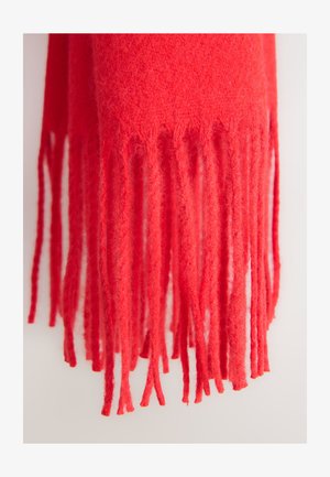 Červená vlnená šála s jemnou texturou, s dlouhými, točenými třásněmi na koncích a rovnoměrnou tloušťkou materiálu po celé délce.