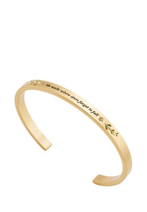 Gold metal cuff bracelet with engraved phrase "she walks where stars forget to fall" and small decorative leaves and stones.