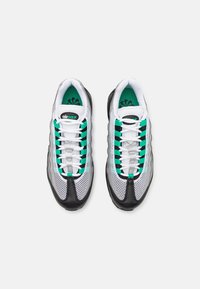 Vita och svarta sneakers med gröna accenter, med en övre del av mesh, vadderad krage och en texturerad gummisula. Snörningsdesign med logodetalj.