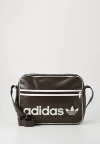 Brun syntetisk skulderveske med hvite glidelåsdetaljer og en fremtredende hvit Adidas-logo. Har en enkelt justerbar stropp og glatt tekstur.