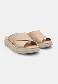 Sandales en cuir beige avec des brides croisées, design ouvert à l'avant et semelle légère. Détails de couture le long du bord.