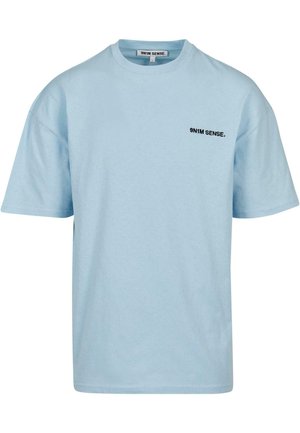 Šviesiai mėlyna trumpomis rankovėmis medvilninė marškinėlių su apvaliu iškirpimu ir mažuoju juodu logotipu ant krūtinės. Paprastas, laisvas siluetas.