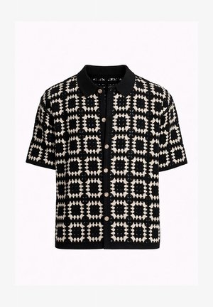 Čiernobiely krátky kardigán na gombíky s geometrickým vzorom štvorcov a jednoliatym čiernym golierom.