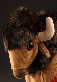 Plush bison toy with brown and tan fur, soft texture, prominent horns, large black eyes, and detailed facial features.