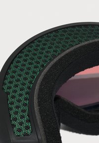 Maschera da sci nera con un cinturino testurizzato verde e nero. Il cinturino presenta un motivo a rete, con imbottitura in schiuma morbida attorno all'oculare.