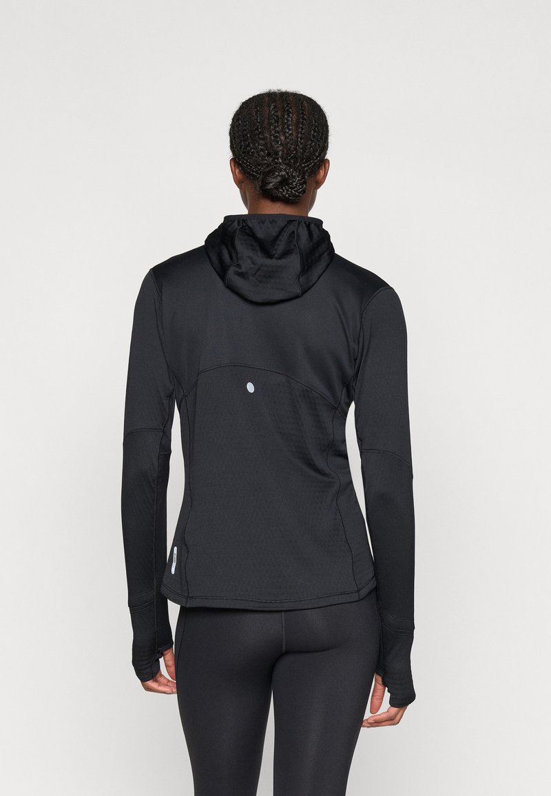 Zwarte sportjack met een getailleerd ontwerp, capuchon, lange mouwen en duimgaten. Getextureerde stof met subtiele details op de achterkant.