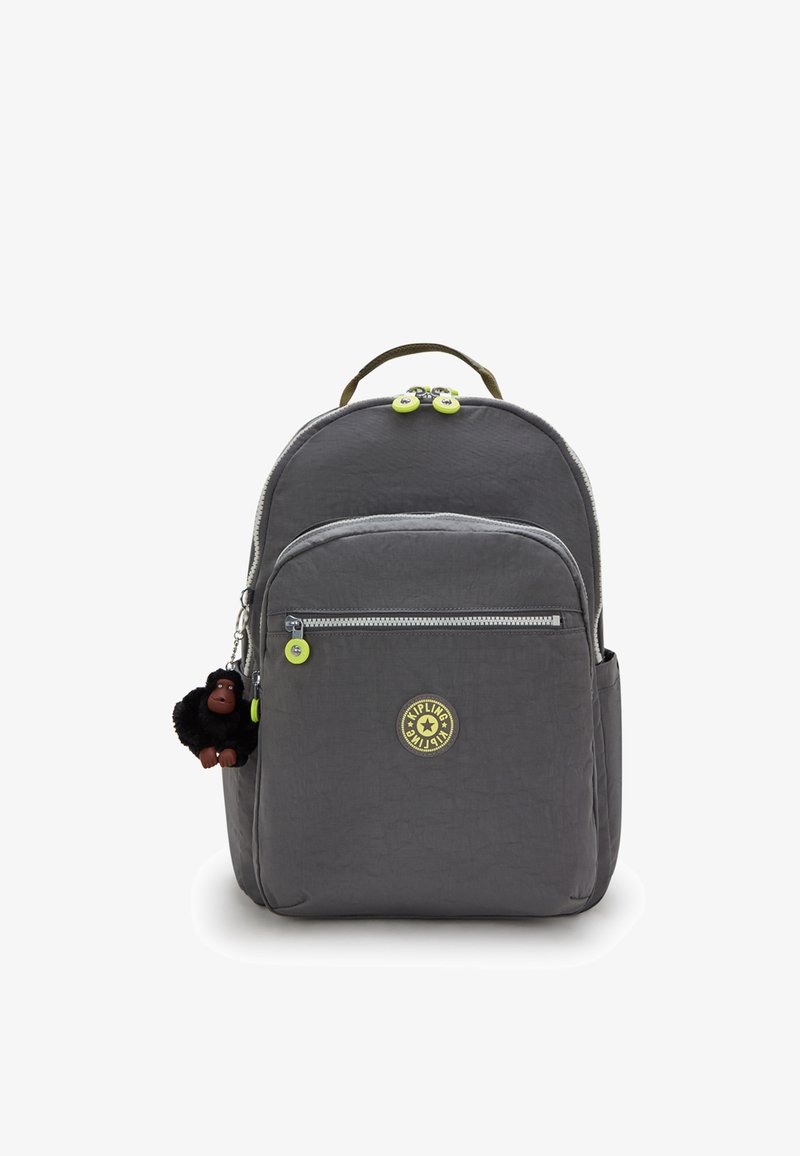 Grå rygsæk med struktureret stof, der har dobbelte lynlåse med grønne træk, logopatch og en sort aber-nøglering som tilbehør.