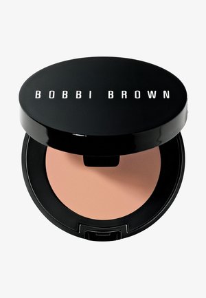Black circular compact featuring the logo "BOBBI BROWN" in white. Inside, a peach-toned powder sits in a smooth, matte finish.
