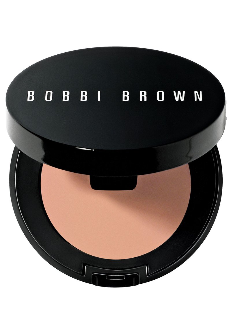 Compact circulaire noir avec le logo "BOBBI BROWN" en blanc. À l'intérieur, une poudre de teinte pêche se trouve dans une finition lisse et mate.