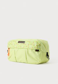 Neon geel-groene tas met bovenkant van geometrisch patroon, ritssluiting, oranje trekband en zwart logohangtag; heeft een geplisseerd design voor textuur.