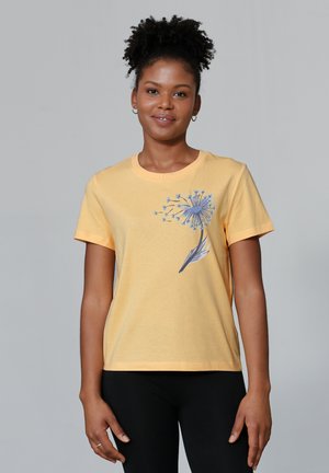T-shirt en coton jaune avec un col rond et des manches courtes. Présente un graphique florale bleue sur le côté gauche de la poitrine. Texture douce.