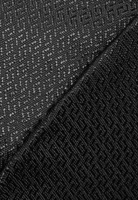Textielstof in zwart en donkergrijs, met een geometrisch patroon en een gladde textuur. Twee secties zijn losjes overlapped.