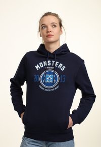 Sudadera de color azul marino con bolsillo tipo canguro, capucha con cordón y un gráfico frontal que presenta "MONSTERS UNIVERSITY" y 2013 en blanco y azul.
