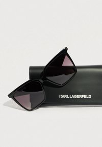 Ochelari de soare negri supradimensionati cu lentile gradient inchise, design unghiular. Insotiti de o husa neagra cu logo-ul "KARL LAGERFELD".