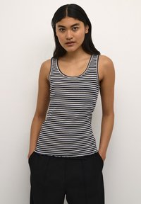Röstripitega tank top tumesinises ja koorekollases, ribakujuline tekstuur, ümar kaelus ja väike laineline äär, millele on sobitatud tumedad püksid.