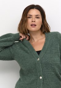 Grøn, fluffy cardigan med V-hals, der har tre runde, teksturerede knapper fortil og puffede ærmer.