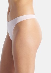 Lichtroze string gemaakt van een gladde, rekbare stof met een zachte tailleband. Biedt minimale bedekking met een naadloos ontwerp.
