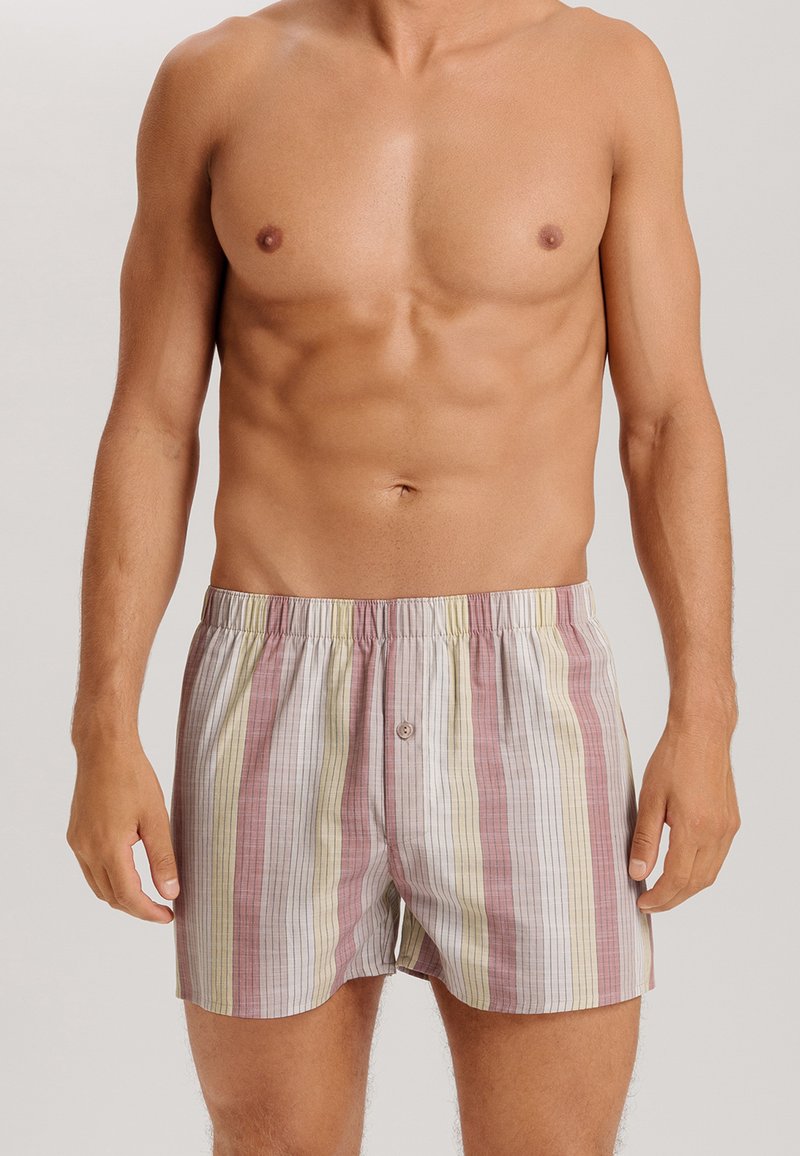 Pantaloni boxer a righe in tessuto morbido, caratterizzati da linee verticali in rosa, giallo e bianco. Girovita elastico con un singolo bottone frontale.