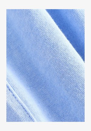 Helles blaugraues Strickgewebe mit glatter Textur und gleichmäßigen Stichen. Leicht gedehnt mit Falten, die seine leichte Qualität zur Geltung bringen.