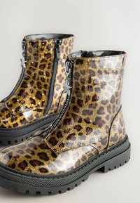 Glitrende leopardprint ankelstøvler med en blank finish, sort lynlås, stjerneformet lynlåsrem og en kraftig sort sål.