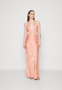 Robe halter en satin rose avec un décolleté en V profond, taille cintrée, et motif de feuilles de palmier. Longueur jusqu'au sol avec une forme fluide et un minimum de détails.