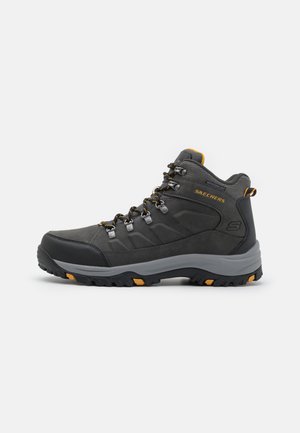 Stivale da trekking nero con accenti grigi, parte superiore texture, lacci vivaci e una suola robusta con dettagli arancioni per trazione e stabilità.