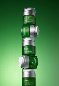 Quatre bocaux verts empilés verticalement, avec des couvercles et des étiquettes en argent. Les bocaux sont étiquetés "Crème de ReSculpt Retinienne de Nuit." Le fond est en dégradé de vert.