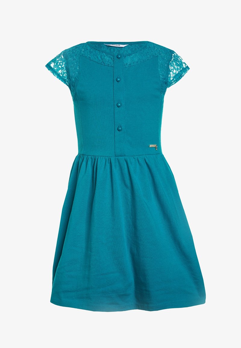 Turkoosi mekko, jossa on lyhyet pitsihihat, pyöreä pääntie, nappi edessä ja pussitettu helma. Silkkinen kangas, jossa on pitsiyksityiskohtia ja hienovarainen tekstuuri.