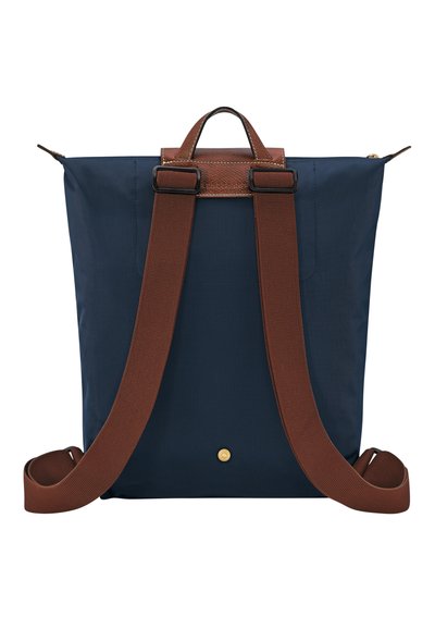 Navy blue nylon backpack with brown leather accents, adjustable brown straps, rectangular shape, and a small gold button detail at the bottom.