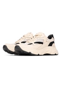 Scarpe da ginnastica beige e nere con elementi in rete e pelle, caratterizzate da una suola spessa e un motivo testurizzato nella parte superiore.
