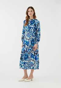 Langärmliges Maxikleid mit floralem Muster in Blau- und Weißtönen. Weicher Stoff mit leichtem Glanz, abgeschlossen mit gerafften Bündchen.