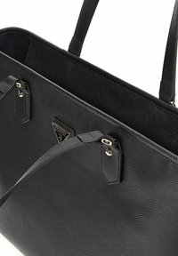 Sac fourre-tout synthétique noir avec une finition texturée, deux poignées et quincaillerie en métal. Présente un insigne logo triangulaire sur le devant.